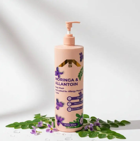 “All People Moringa & Allantoin Body Wash bottle with pump, surrounded by moringa leaves and purple flowers on a soft white background.”