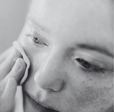 Close-up of a person's face with a hand on their cheek, in black and white.