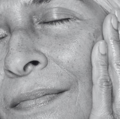Close-up of a person's face with a hand touching their cheek, in black and white.