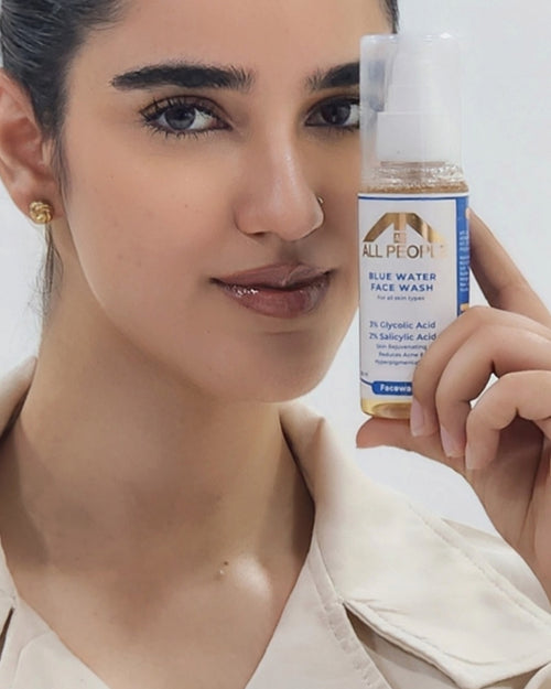 Woman holding a bottle of All People Blue Water Face Wash against a neutral background