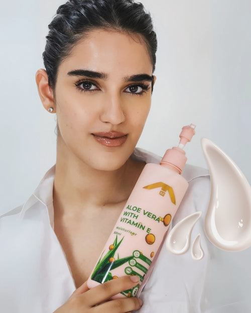 Woman holding a bottle of skincare product with a plain background
